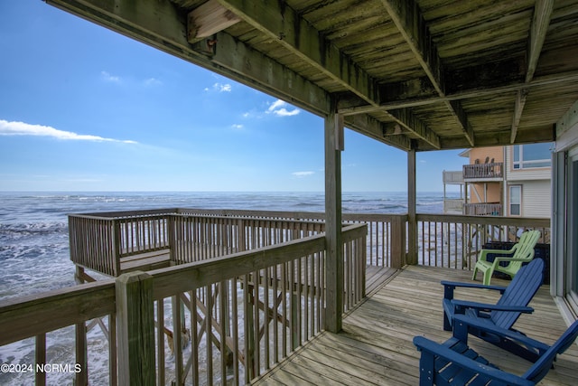 exterior space featuring a deck with water view and a beach view