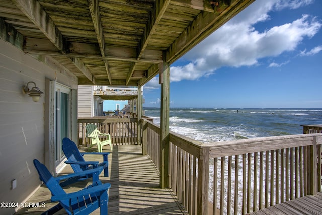 wooden terrace featuring a view of the beach and a water view