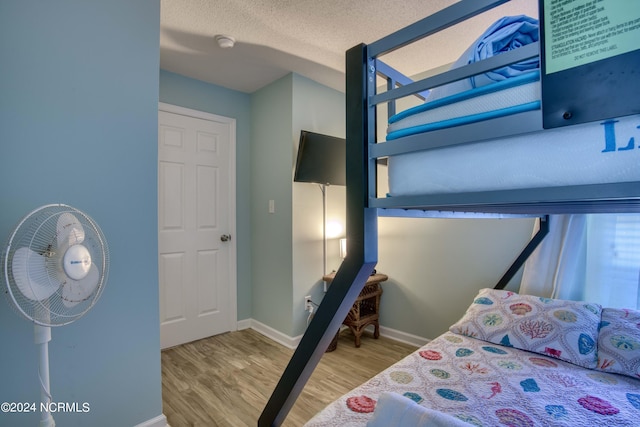 bedroom featuring baseboards, a textured ceiling, and wood finished floors