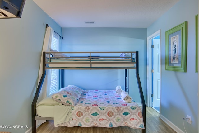 bedroom featuring a textured ceiling, multiple windows, and hardwood / wood-style flooring