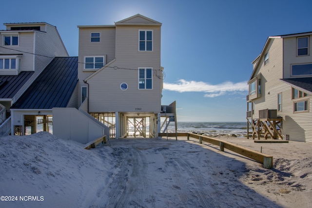 back of property featuring a view of the beach and a water view