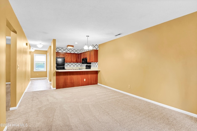 kitchen featuring light colored carpet, kitchen peninsula, black appliances, tasteful backsplash, and decorative light fixtures