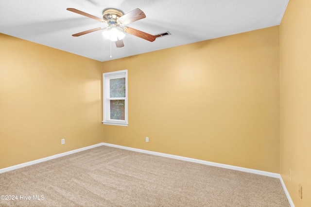 carpeted spare room featuring ceiling fan and a textured ceiling