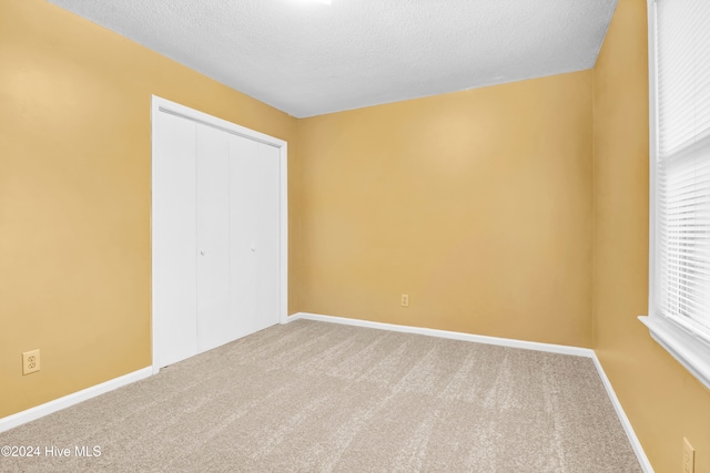 unfurnished bedroom with carpet, a textured ceiling, and a closet