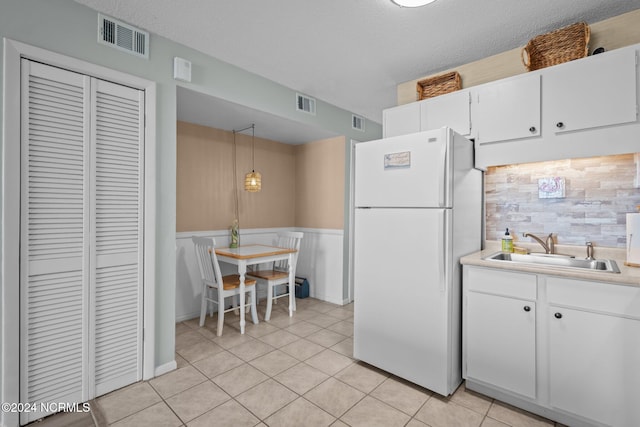 kitchen with sink, a textured ceiling, decorative light fixtures, white cabinetry, and white fridge