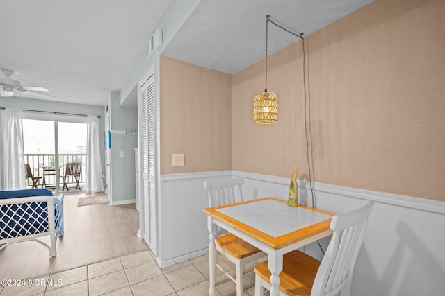 tiled dining room with ceiling fan with notable chandelier