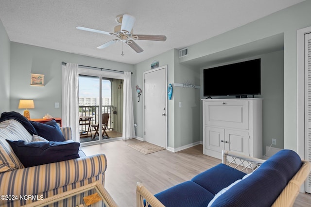 living room with light hardwood / wood-style flooring, a textured ceiling, and ceiling fan