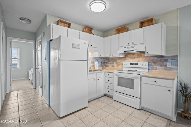 kitchen featuring white appliances, premium range hood, light tile patterned floors, and white cabinetry