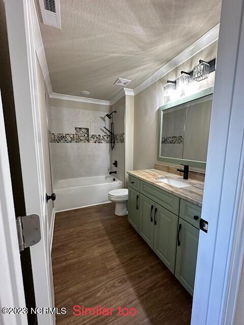 full bathroom with tiled shower / bath, vanity, toilet, ornamental molding, and hardwood / wood-style floors