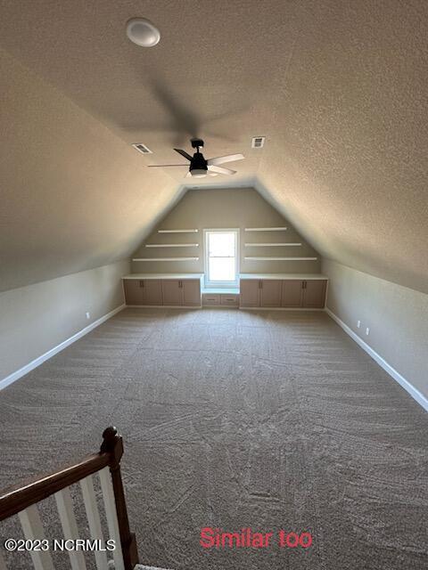 bonus room featuring lofted ceiling, ceiling fan, carpet floors, and a textured ceiling