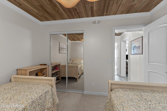 carpeted bedroom with a closet, crown molding, wooden ceiling, and baseboards