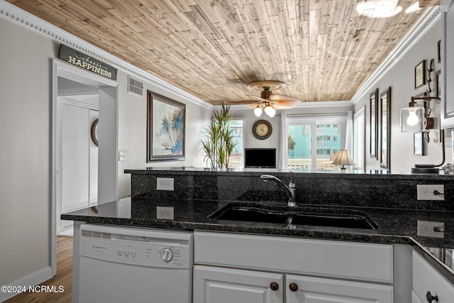 kitchen featuring dishwasher, a sink, ornamental molding, wood finished floors, and dark stone counters