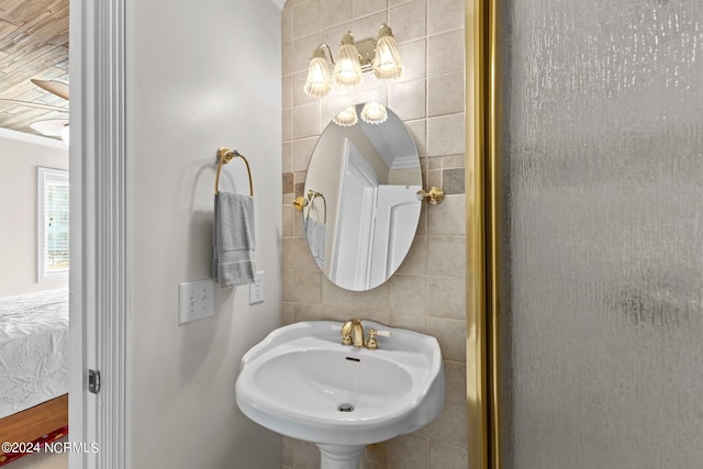 bathroom featuring a sink, tile walls, and ornamental molding