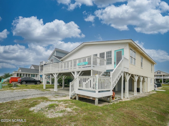 rear view of property with a wooden deck, a carport, and a yard