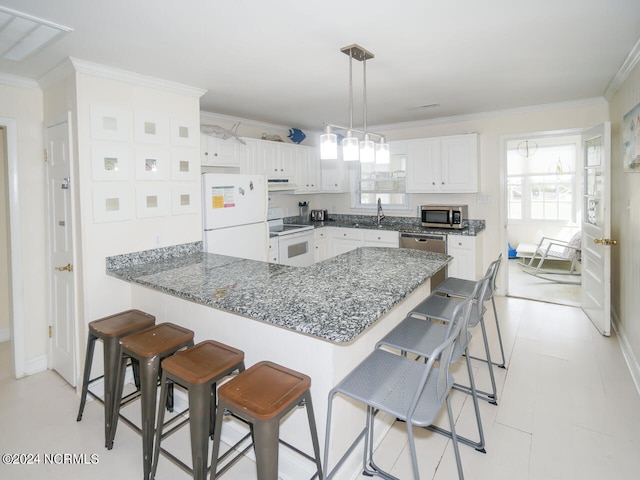 kitchen featuring kitchen peninsula, white cabinets, appliances with stainless steel finishes, a kitchen breakfast bar, and ornamental molding