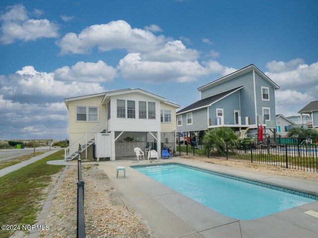 rear view of property with a patio area and a fenced in pool