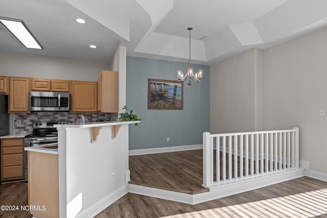 kitchen with backsplash, appliances with stainless steel finishes, dark hardwood / wood-style flooring, kitchen peninsula, and a breakfast bar area