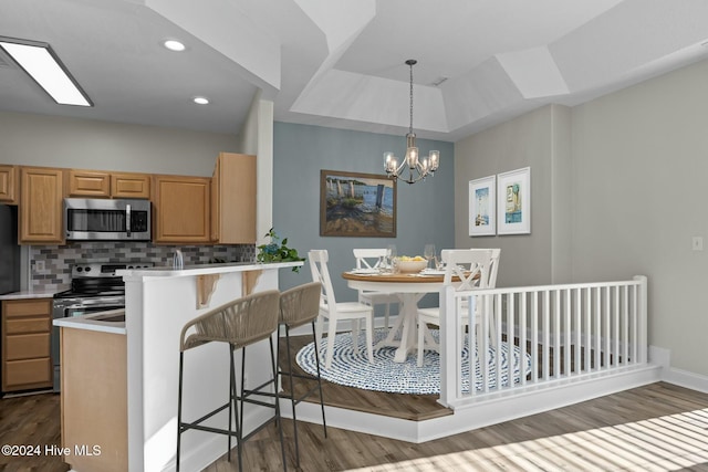 kitchen with a kitchen bar, appliances with stainless steel finishes, dark hardwood / wood-style flooring, tasteful backsplash, and a notable chandelier