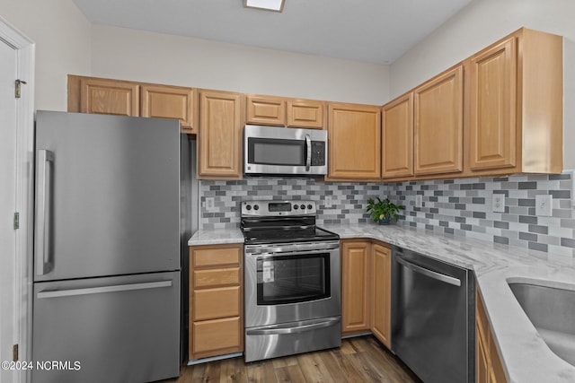 kitchen featuring sink, decorative backsplash, light stone counters, appliances with stainless steel finishes, and dark hardwood / wood-style flooring