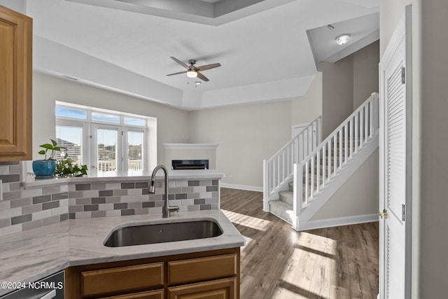 kitchen with backsplash, stainless steel dishwasher, ceiling fan, sink, and hardwood / wood-style floors