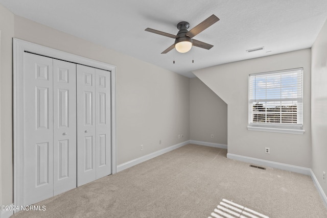 interior space featuring ceiling fan, light colored carpet, and a textured ceiling