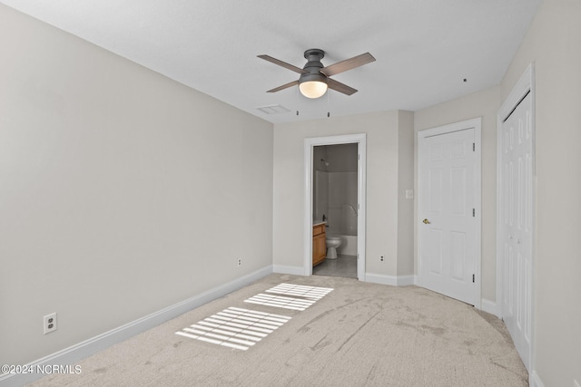 unfurnished bedroom with ensuite bathroom, ceiling fan, light carpet, and a closet