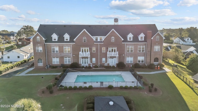 back of property featuring a fenced in pool and a yard