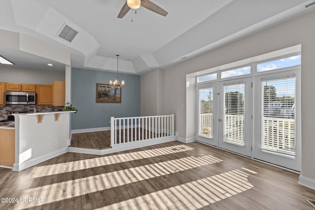 kitchen with pendant lighting, backsplash, ceiling fan with notable chandelier, light wood-type flooring, and appliances with stainless steel finishes