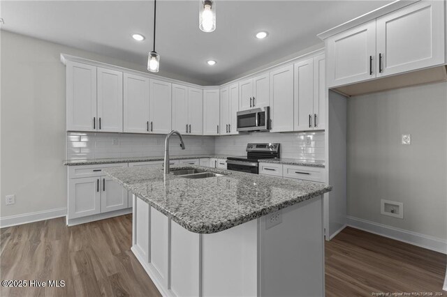 kitchen with appliances with stainless steel finishes, decorative light fixtures, and white cabinetry