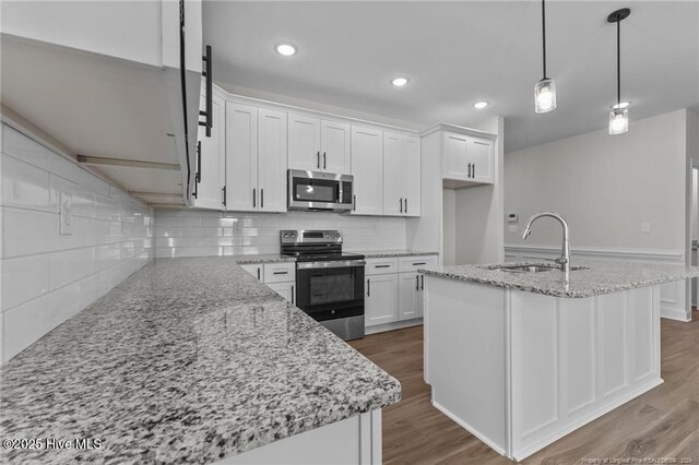 kitchen featuring white cabinets, appliances with stainless steel finishes, a kitchen island with sink, and sink