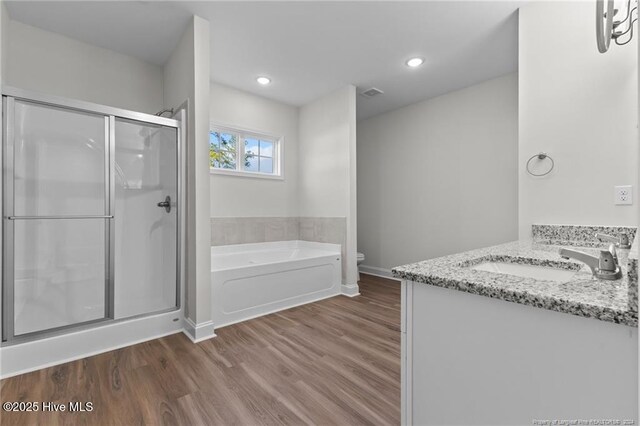 full bathroom featuring plus walk in shower, vanity, hardwood / wood-style flooring, and toilet