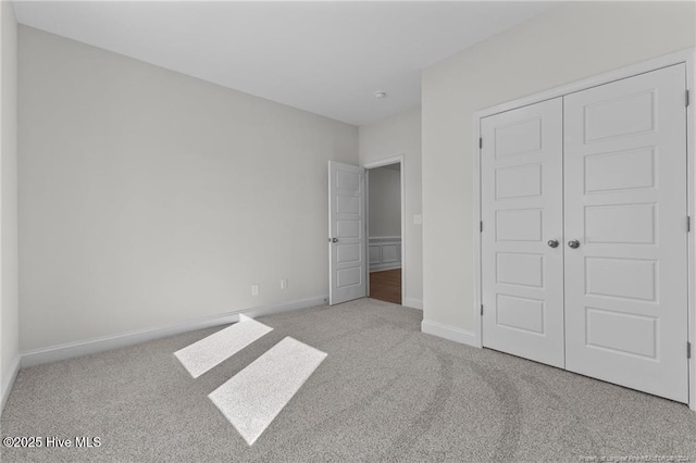 unfurnished bedroom with a closet and light colored carpet