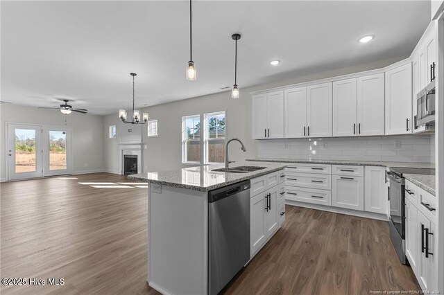 kitchen with white cabinets, appliances with stainless steel finishes, a center island with sink, and ceiling fan