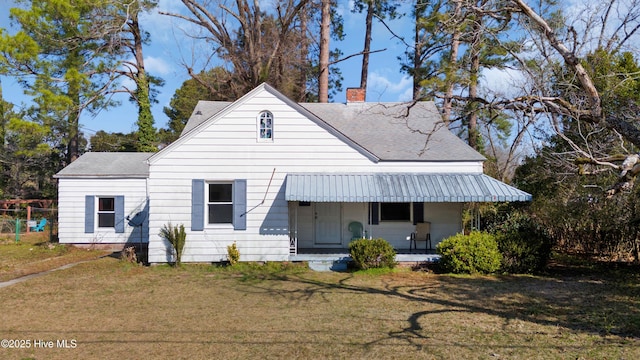 view of front facade featuring a shingled roof, a chimney, a porch, and a front yard