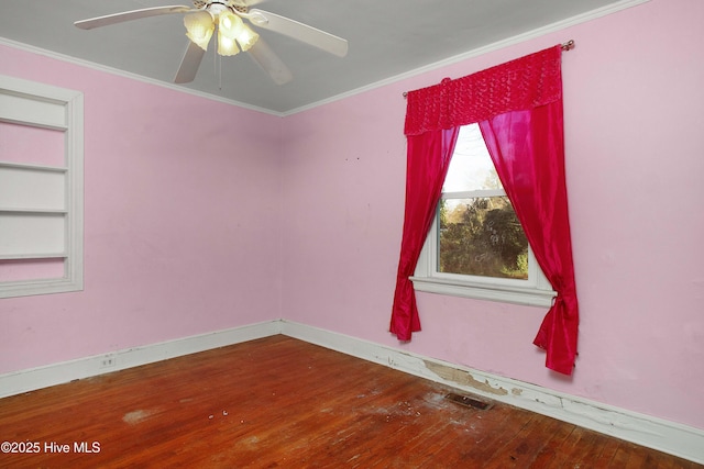 empty room featuring ornamental molding, wood-type flooring, built in shelves, and baseboards