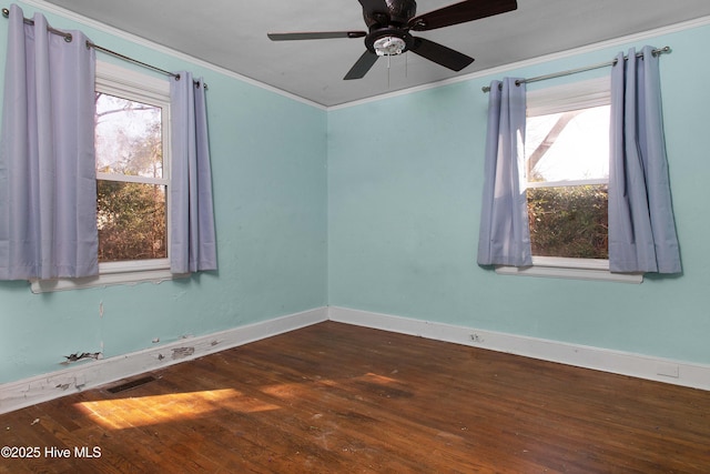 spare room featuring crown molding, visible vents, a ceiling fan, wood finished floors, and baseboards