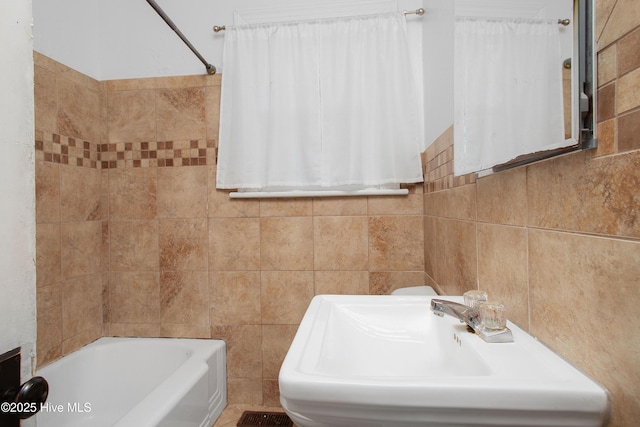 full bath with a tub, tile walls, and a sink