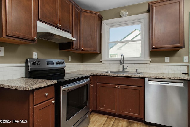 kitchen featuring stainless steel appliances, backsplash, a sink, and under cabinet range hood