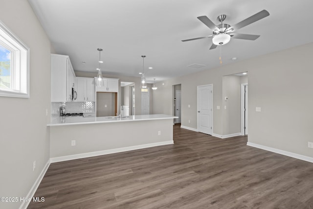 unfurnished living room featuring ceiling fan, baseboards, dark wood-type flooring, and a sink