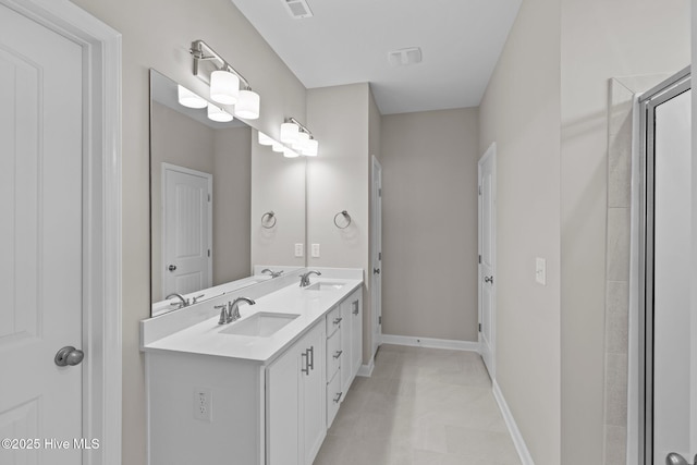 full bath with double vanity, a sink, visible vents, and baseboards