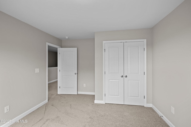 unfurnished bedroom featuring carpet, a closet, and baseboards