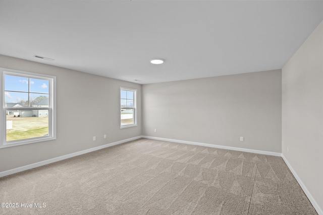 empty room with light carpet, visible vents, and baseboards