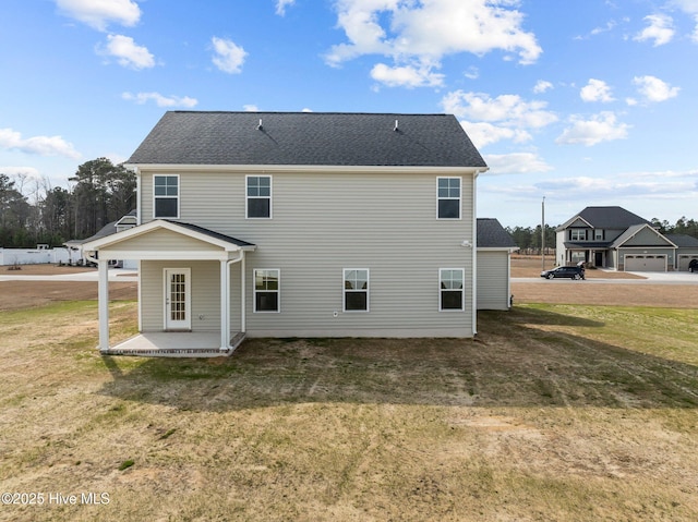 rear view of house with a yard and roof with shingles