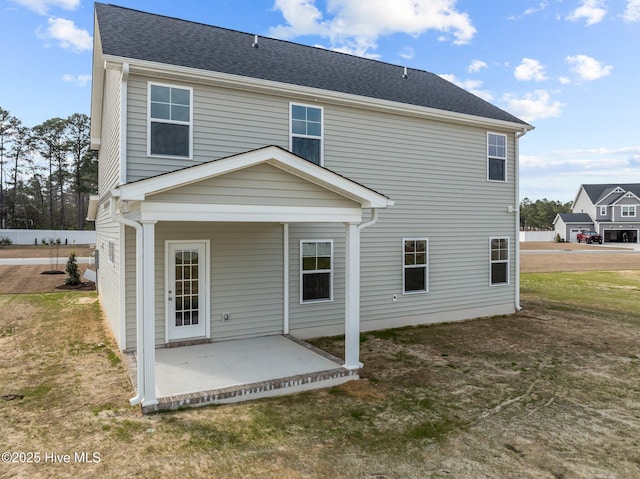 rear view of property featuring a shingled roof and a patio area