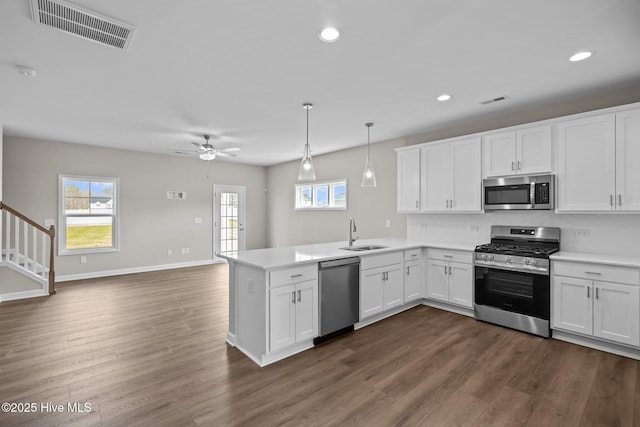 kitchen with stainless steel appliances, a peninsula, a sink, visible vents, and white cabinets