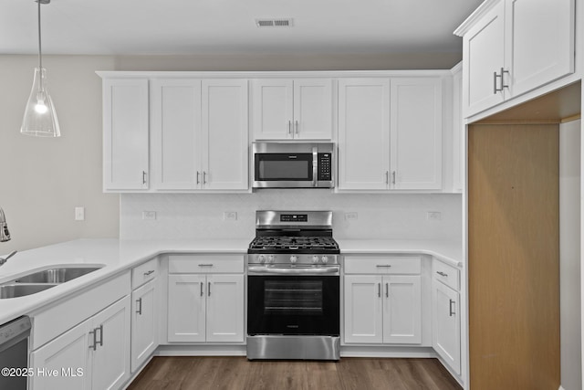 kitchen featuring dark wood finished floors, stainless steel appliances, visible vents, white cabinets, and a sink