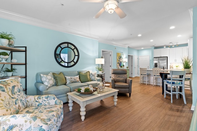 living room featuring ceiling fan, ornamental molding, and light hardwood / wood-style floors