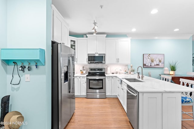 kitchen featuring stainless steel appliances, light hardwood / wood-style floors, tasteful backsplash, and white cabinetry