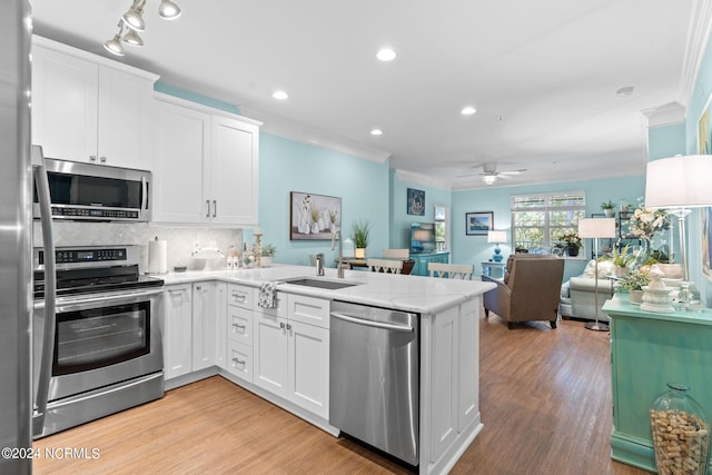 kitchen featuring kitchen peninsula, appliances with stainless steel finishes, sink, and white cabinetry