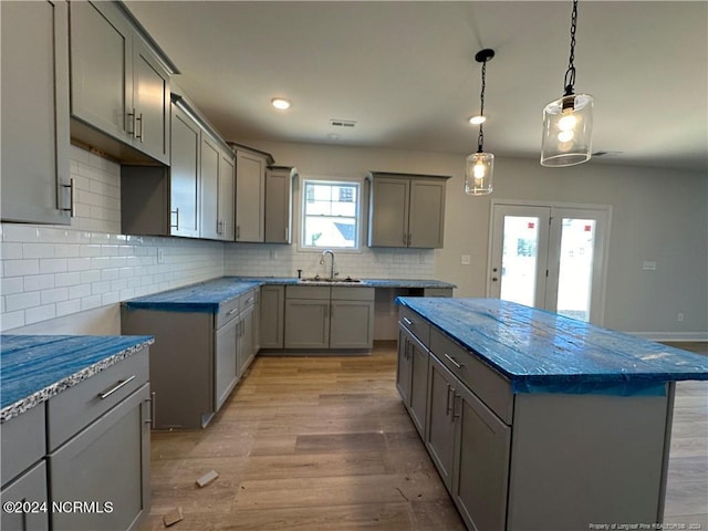 kitchen with a center island, light hardwood / wood-style flooring, gray cabinetry, and backsplash